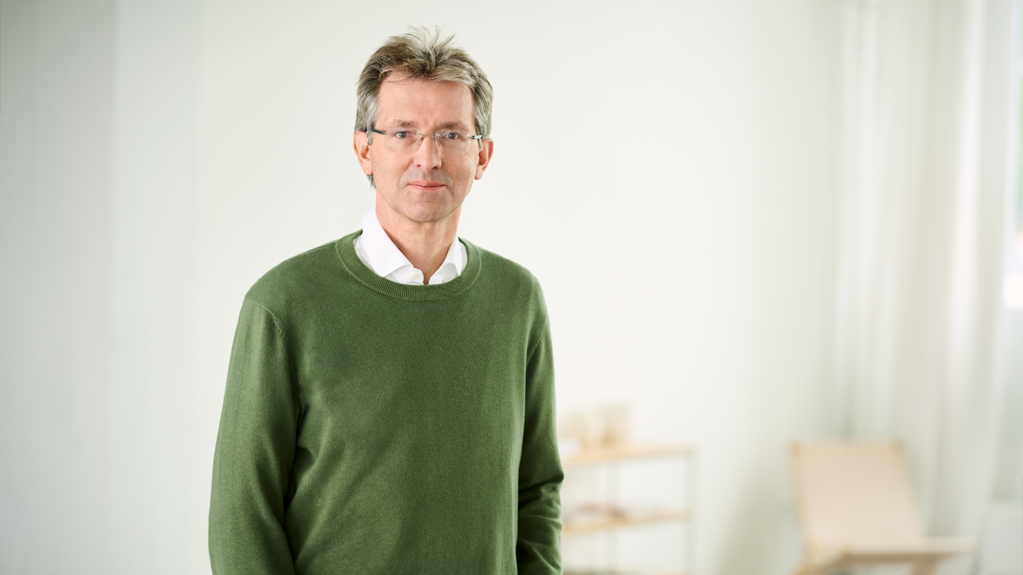 Justus Hecking-Veltman, CFO, dans une pièce lumineuse, vêtu d’un pull vert foncé et d’une chemise blanche.