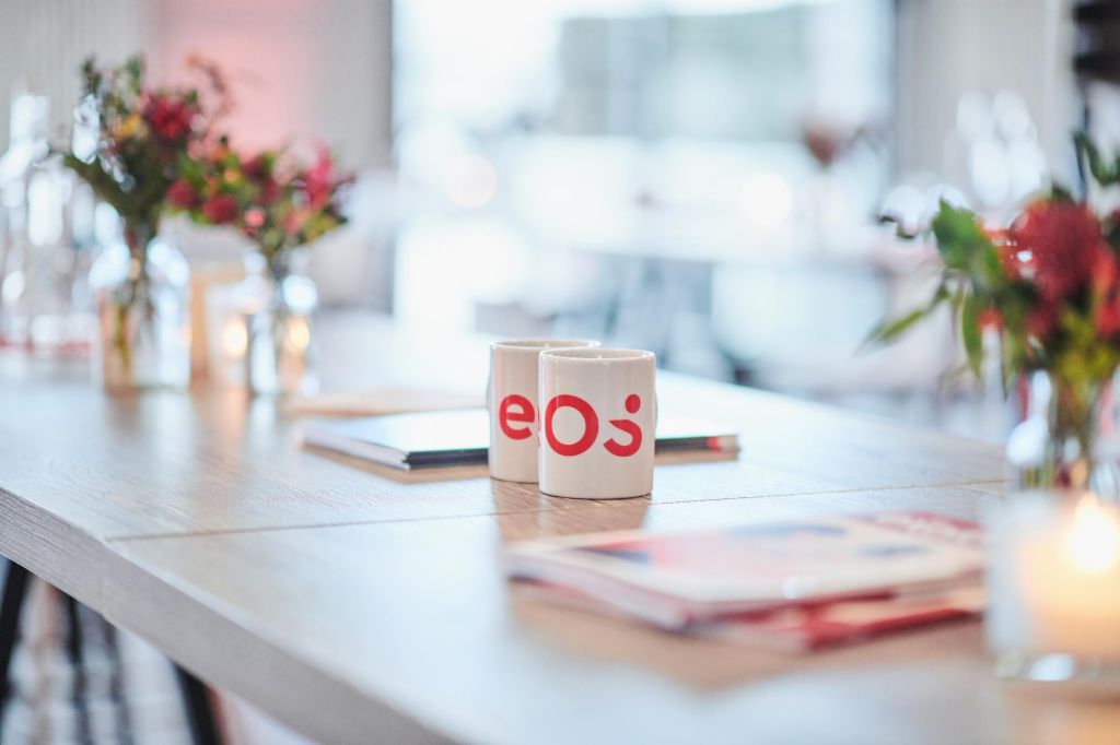 Two white cups with the new EOS logo are standing on a table
