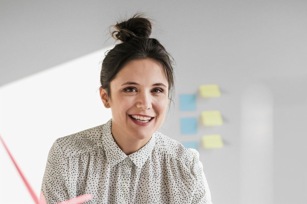Portrait d'une jeune employée souriante d'EOS avec un modèle d'éolienne sur le bureau
